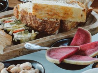 Cowhorn Supper Club's Bread & Snack Service features hearth-fired bread, Cowhorn cultured butter, marinated olives, Carta di musica, vegetable Terrine, hearth-fired almonds, and more.