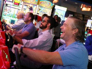 Adults play arcade games at Main Event.