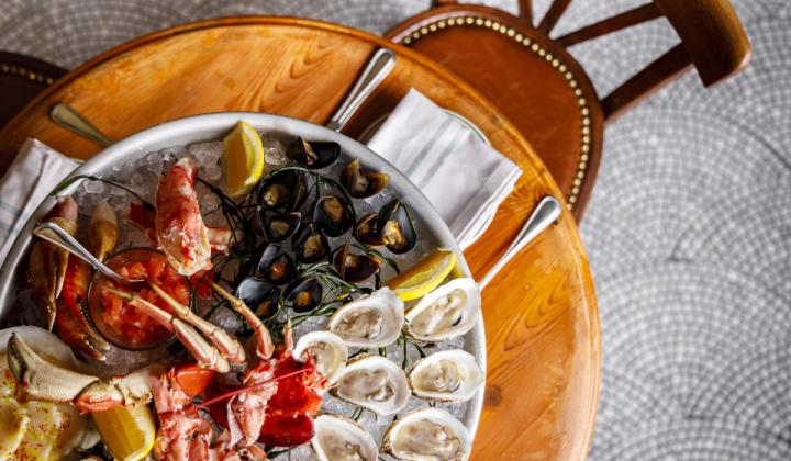 A platter of seafood like lobster and oysters on a wooden table.